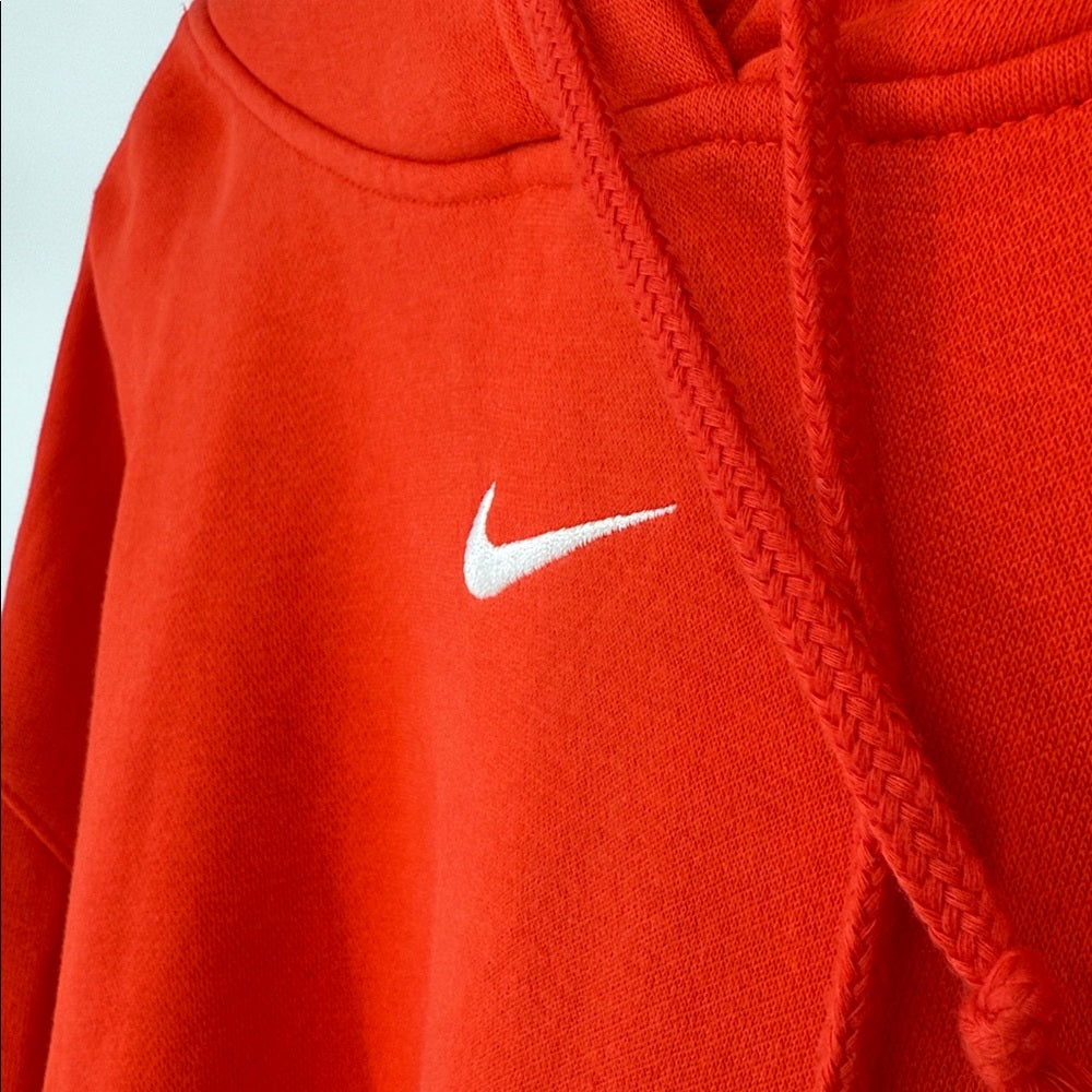 Close-up of a red hoodie with a white Nike logo on a light blue background