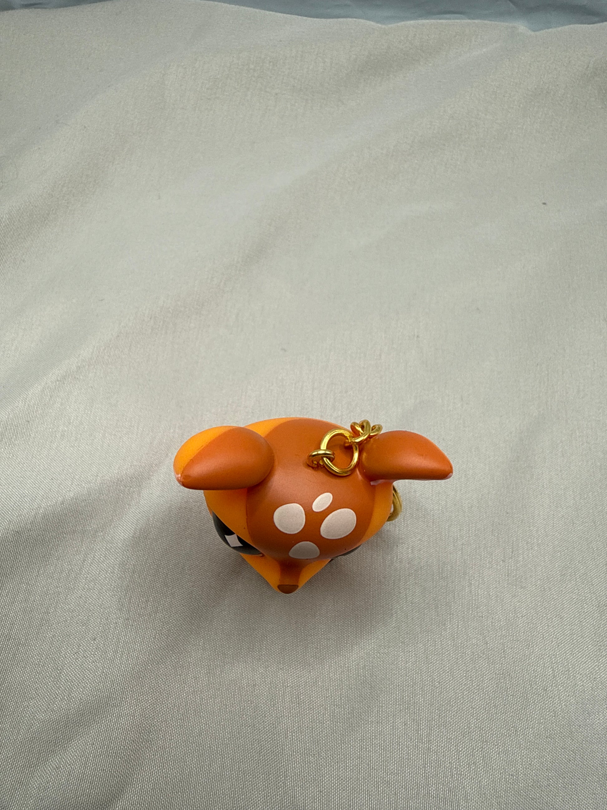 Small brown animal figurine with white spots  on a light gray background