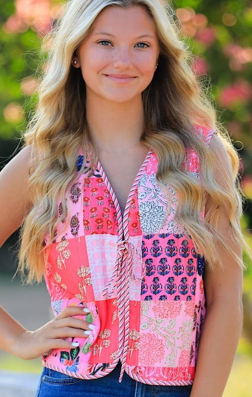 Woman wearing a colorful patchwork vest with a blurred natural background