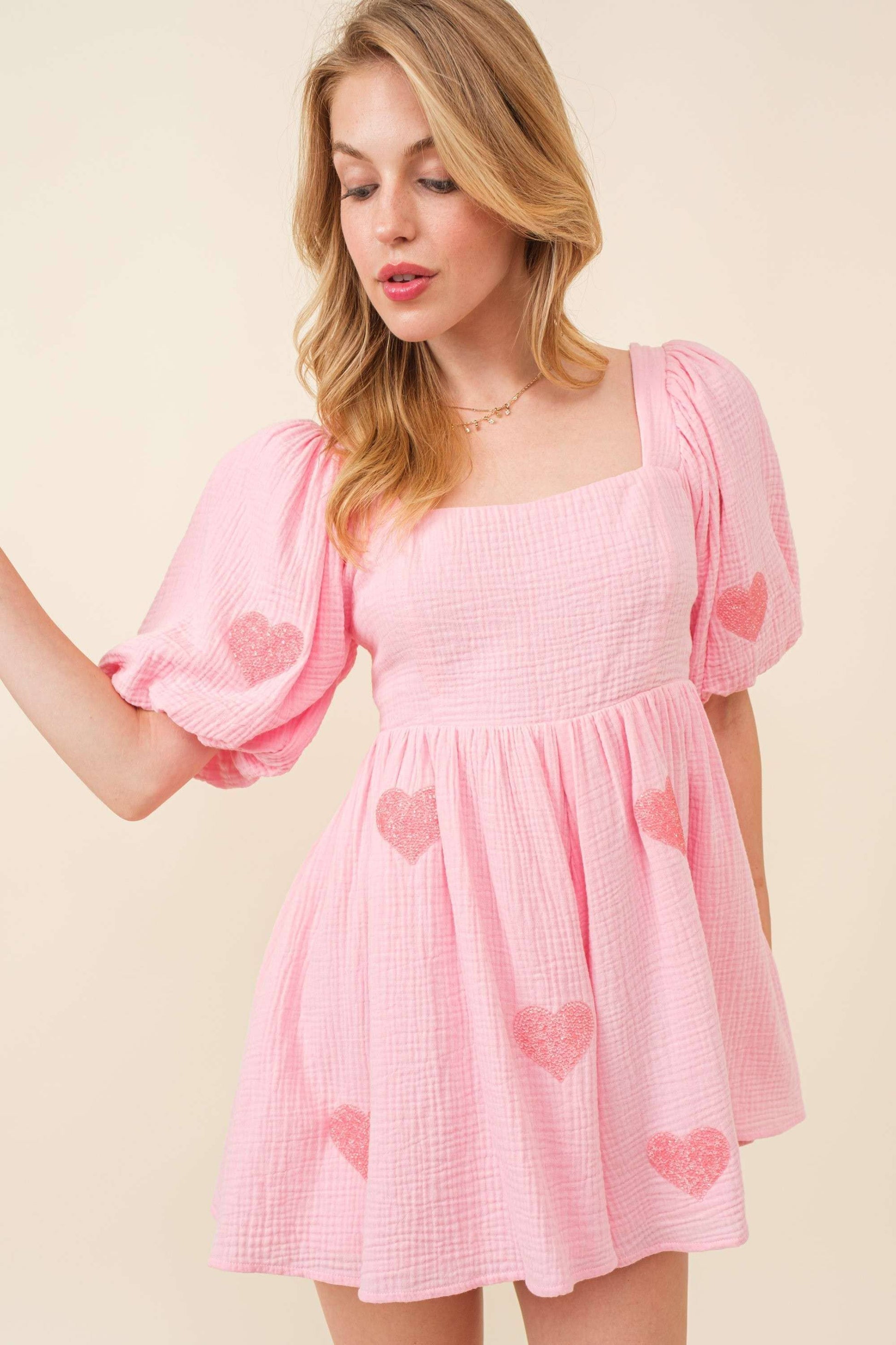 Woman wearing a pink dress with heart patterns on a beige background