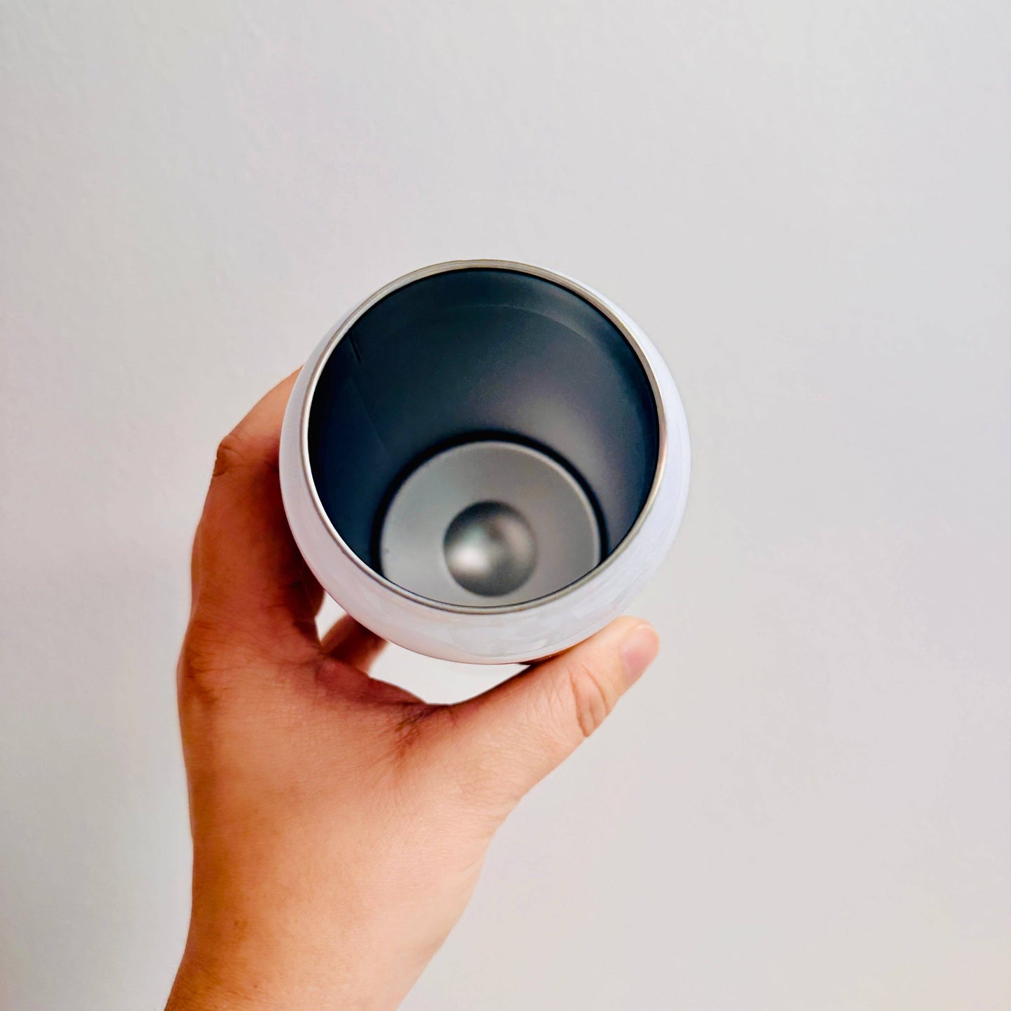 Hand holding a white and blue tumbler against a plain background