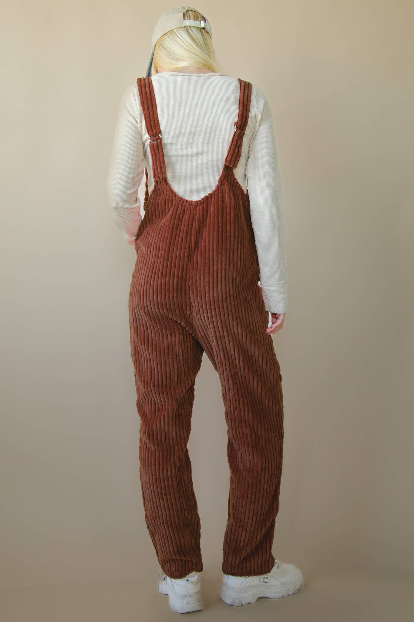 Back of brown corduroy overalls on model on cream background 