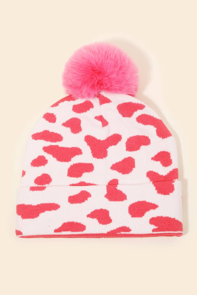 Pink and white cow print pom beanie on a beige background  