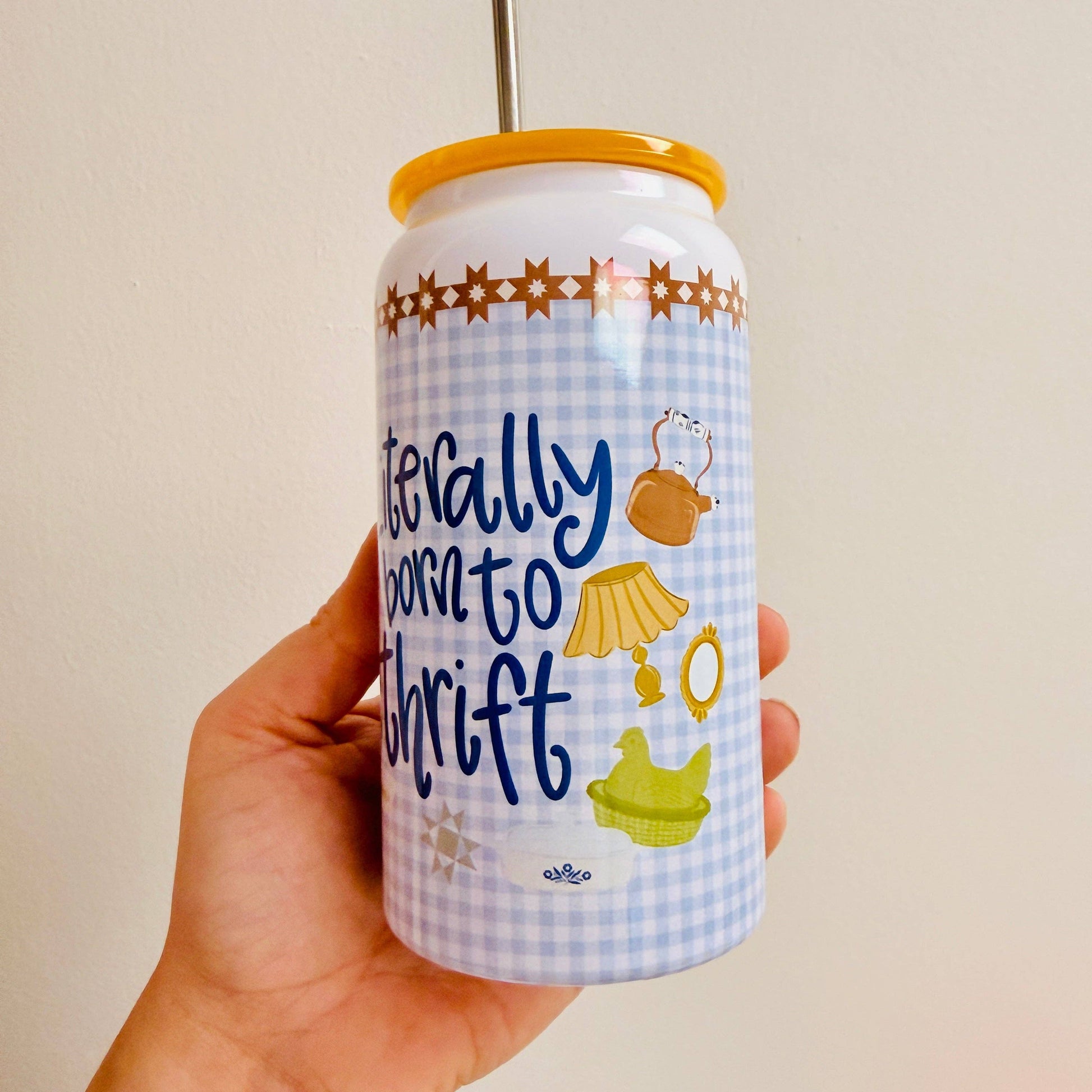 Hand holding a can with decorative design and text against a plain background