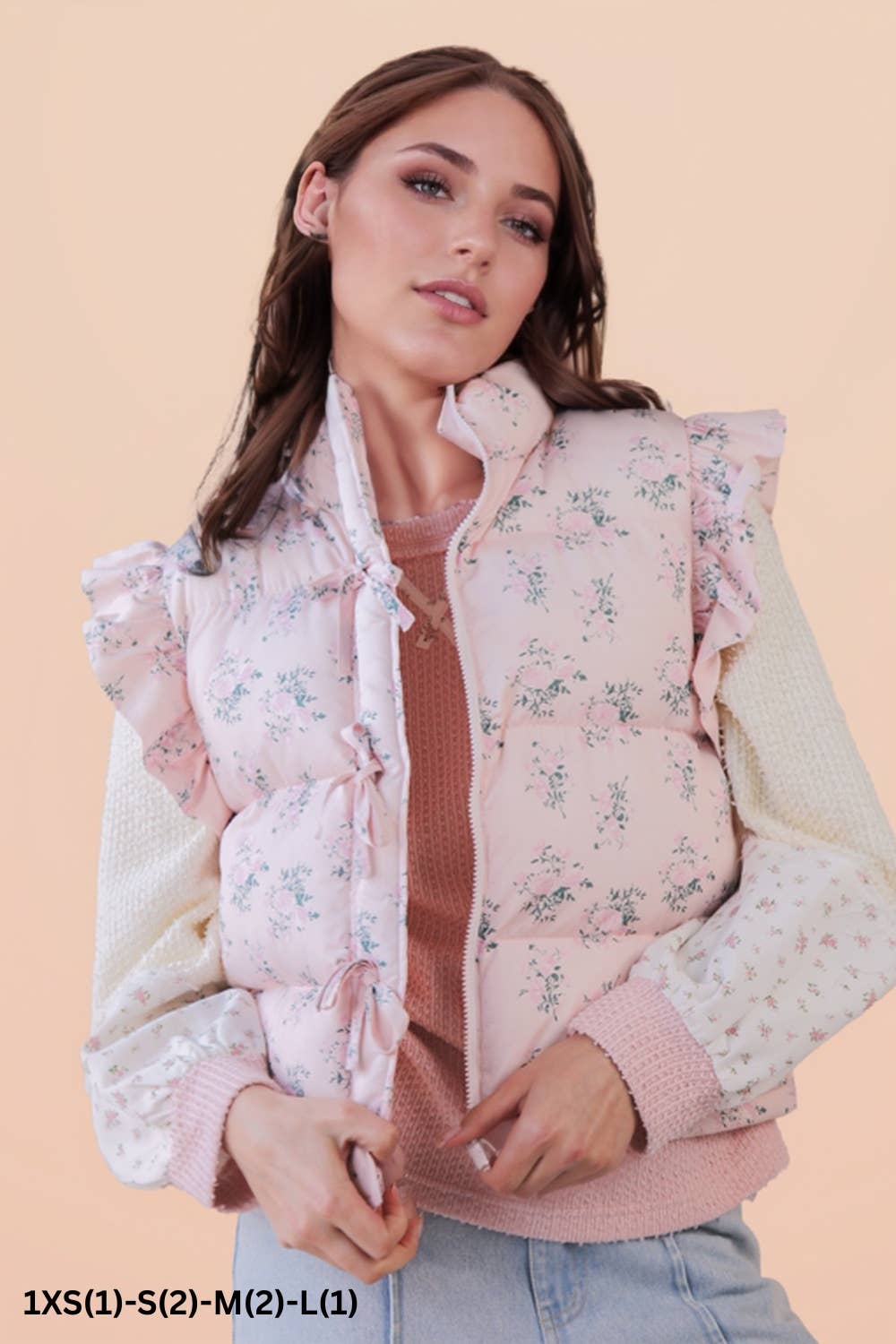 pink floral puffer vest with bows down the front on model with brown hair on a beige background 