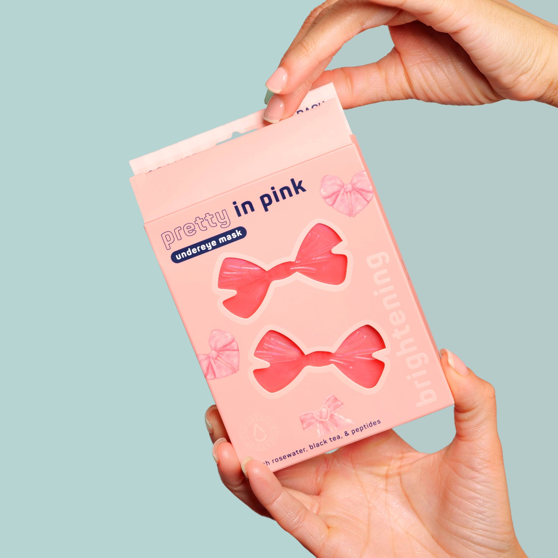 Hand holding a pink packaging of 'pretty in pink' underwears against a light blue background