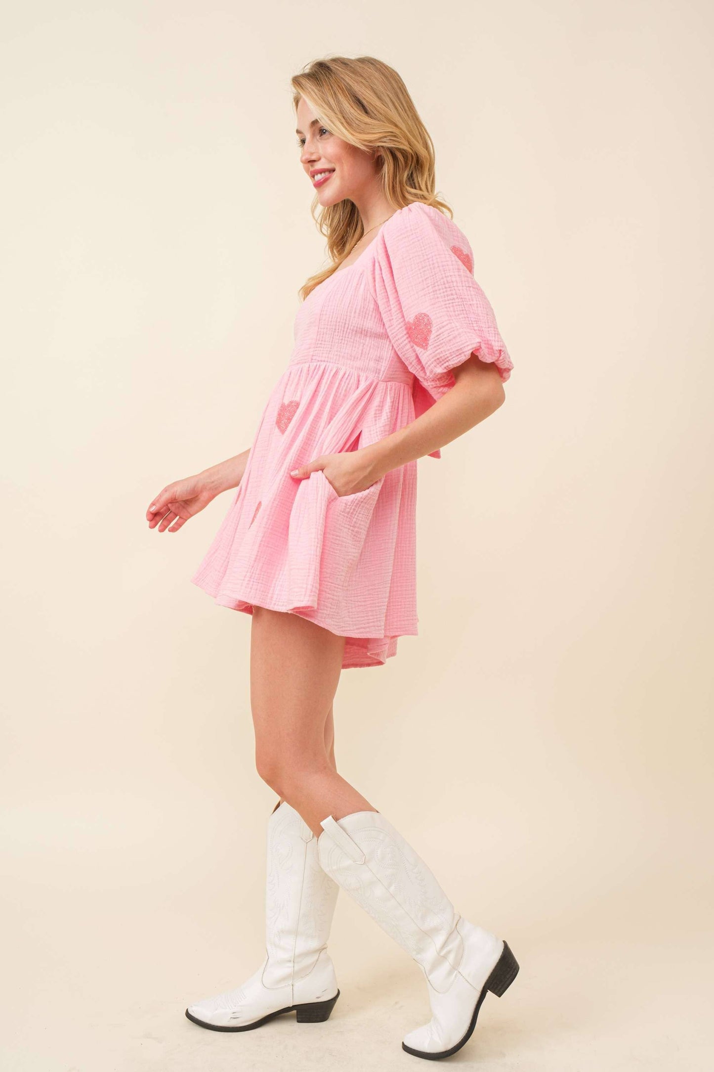 Woman wearing a pink dress and white boots on a beige background