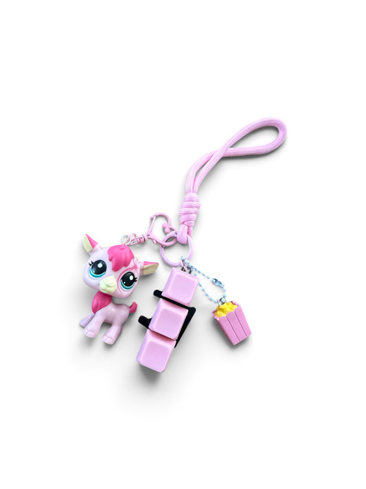 A pink and white cartoon pony keychain charm with a wrist strap, attached to a pink seat and popcorn bucket accessory on a white background.