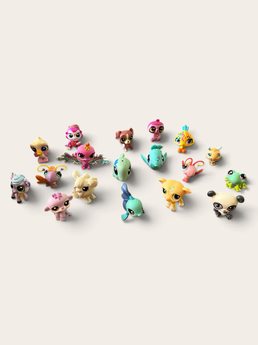A collection of small, colorful animal-shaped toy figures arranged on a plain light beige background.