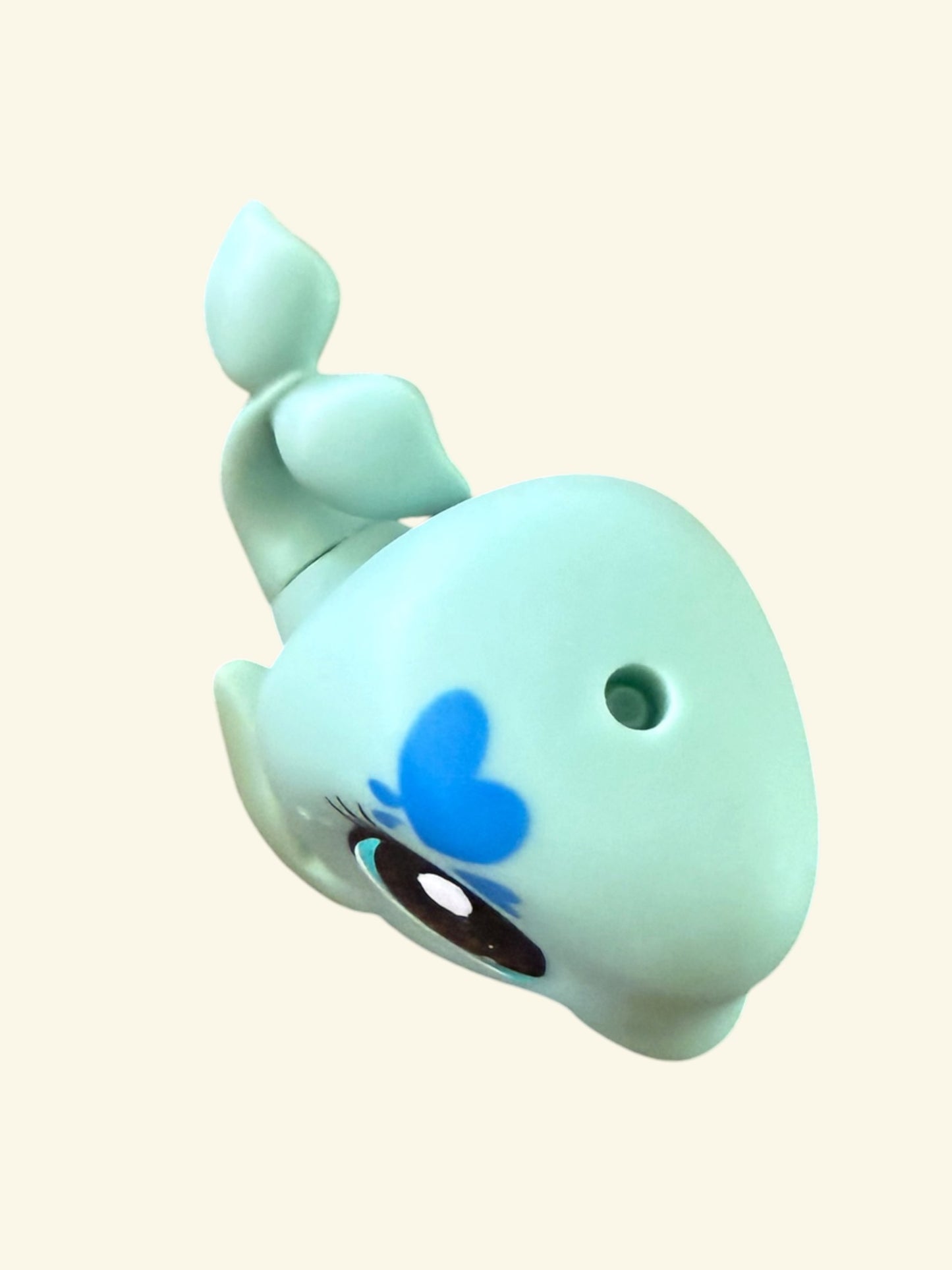 A light blue whale-shaped novelty item with a blue heart on its forehead, a large cartoon eye, and a small hole near its head, shown on a plain cream background.