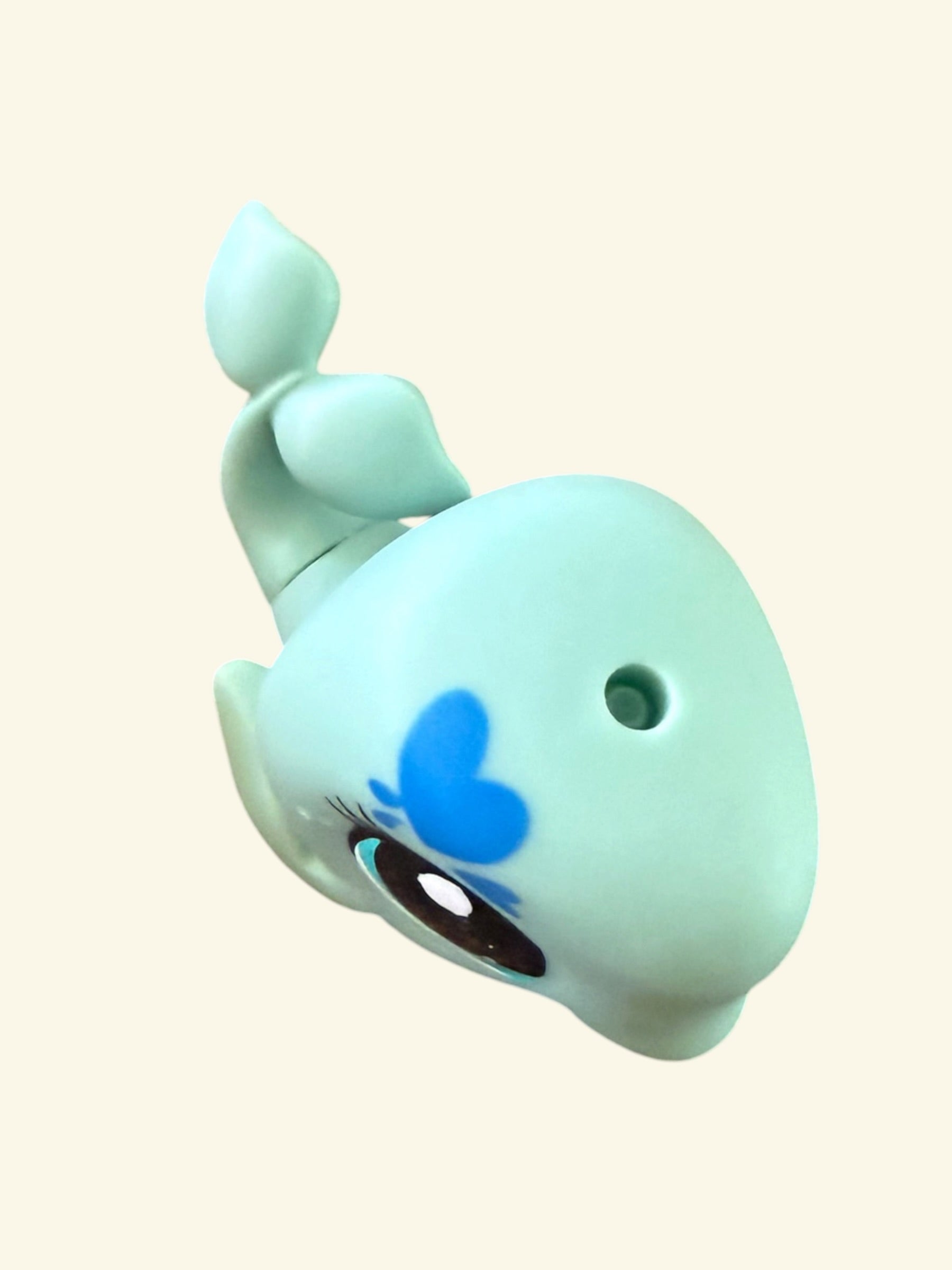 A light blue whale-shaped novelty item with a blue heart on its forehead, a large cartoon eye, and a small hole near its head, shown on a plain cream background.
