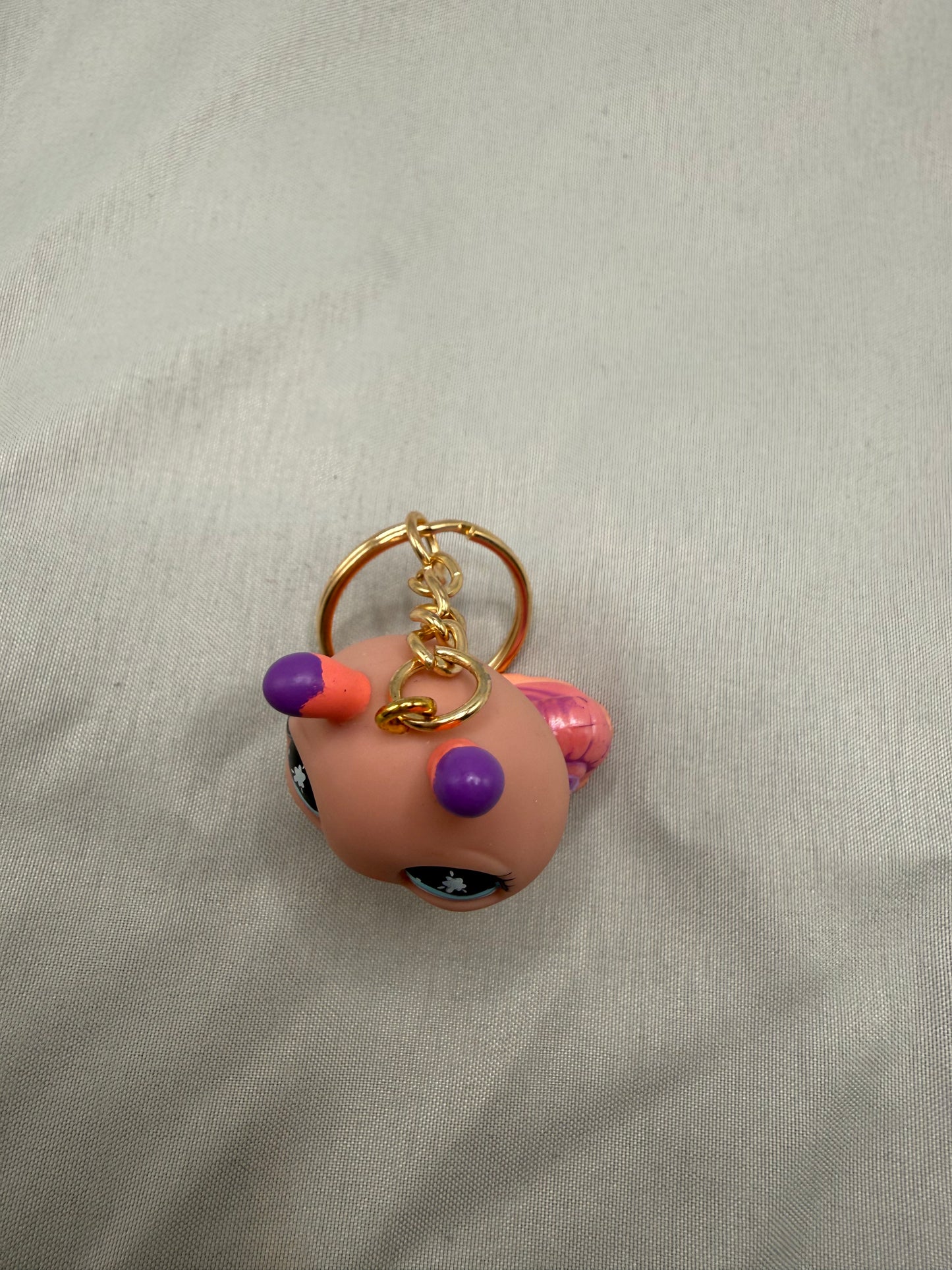 Small snail keychain with a gold ring on a beige fabric background
