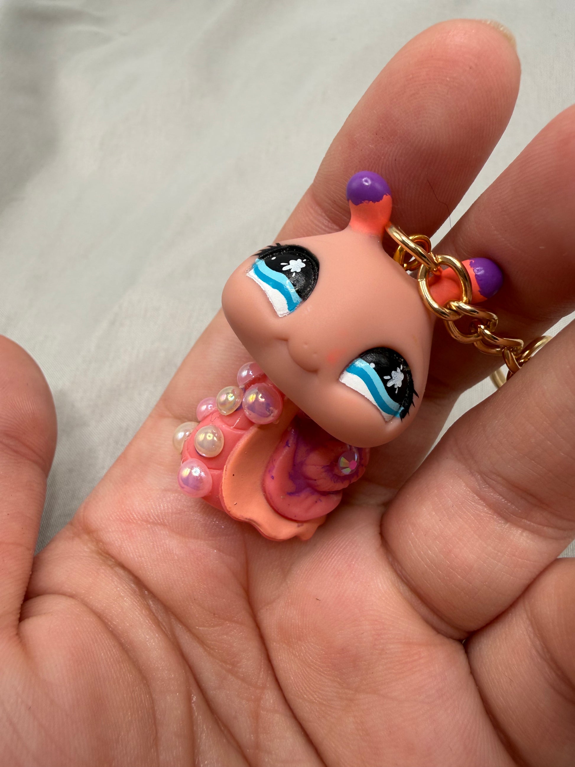 Small figurine of a character with colorful makeup held in a hand against a neutral background