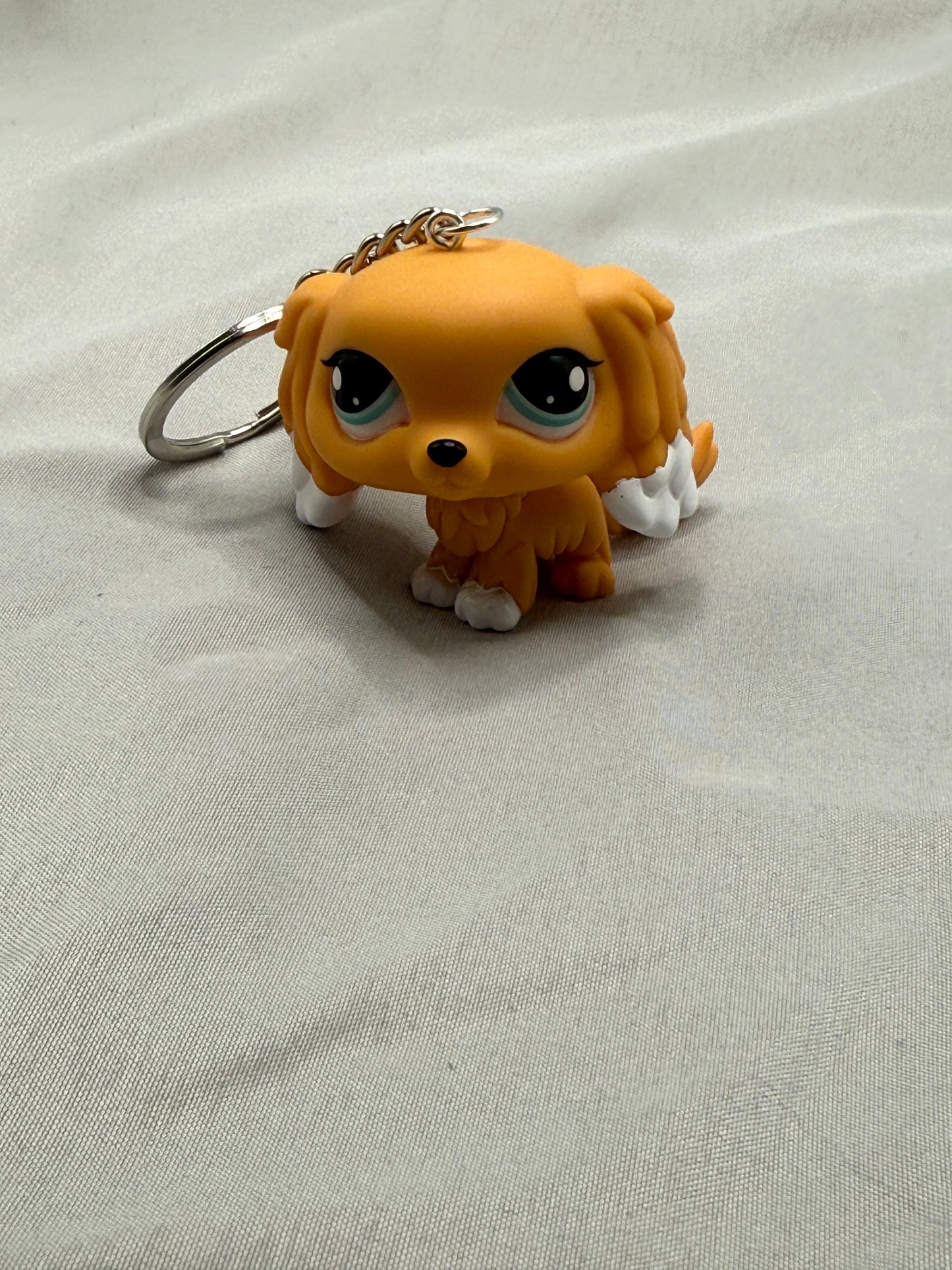 Small orange dog figurine keychain on a light gray fabric background