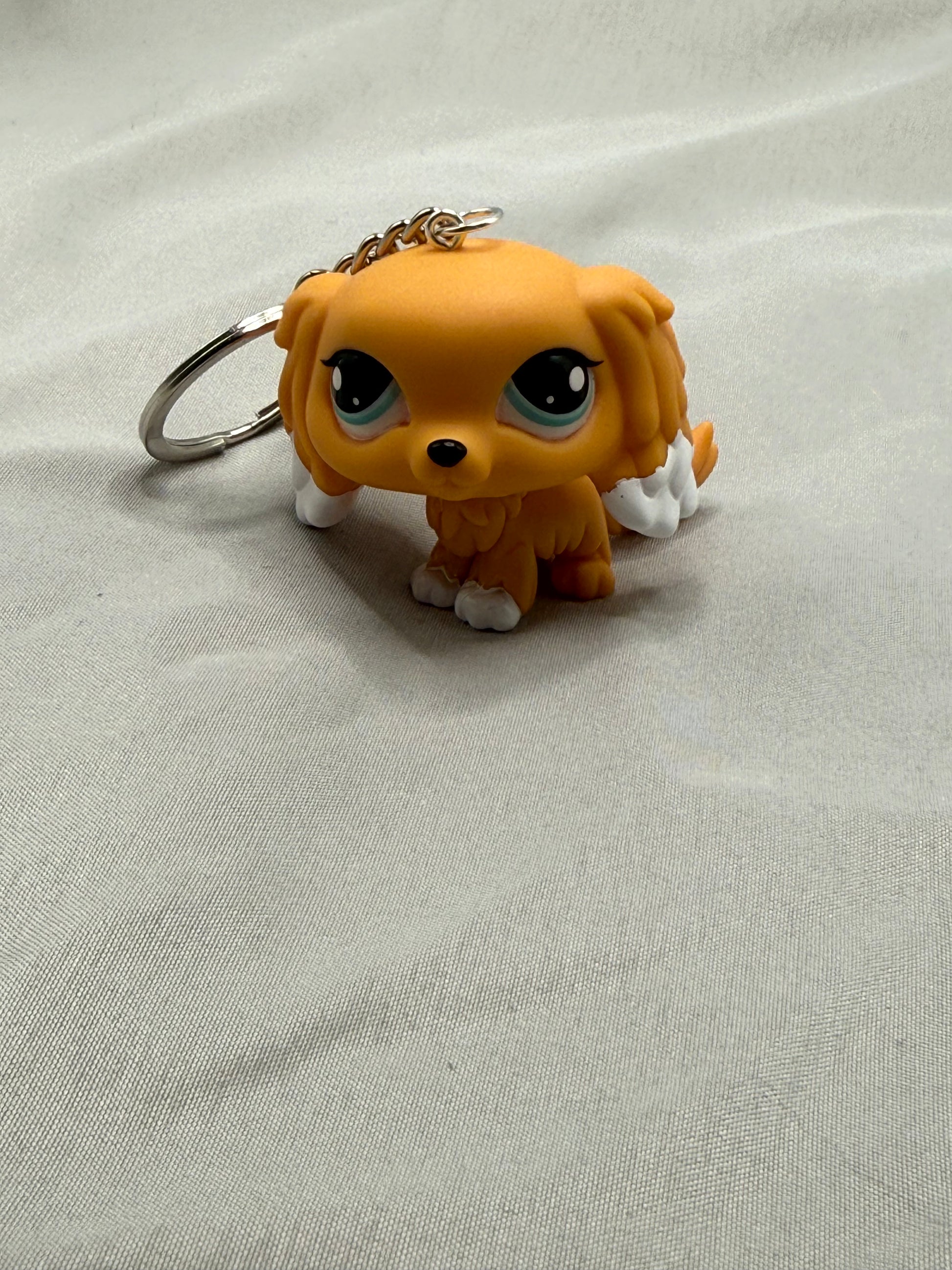 Small orange dog figurine keychain on a light gray fabric background