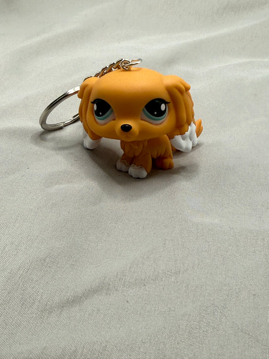 Small orange dog figurine keychain on a light gray fabric background