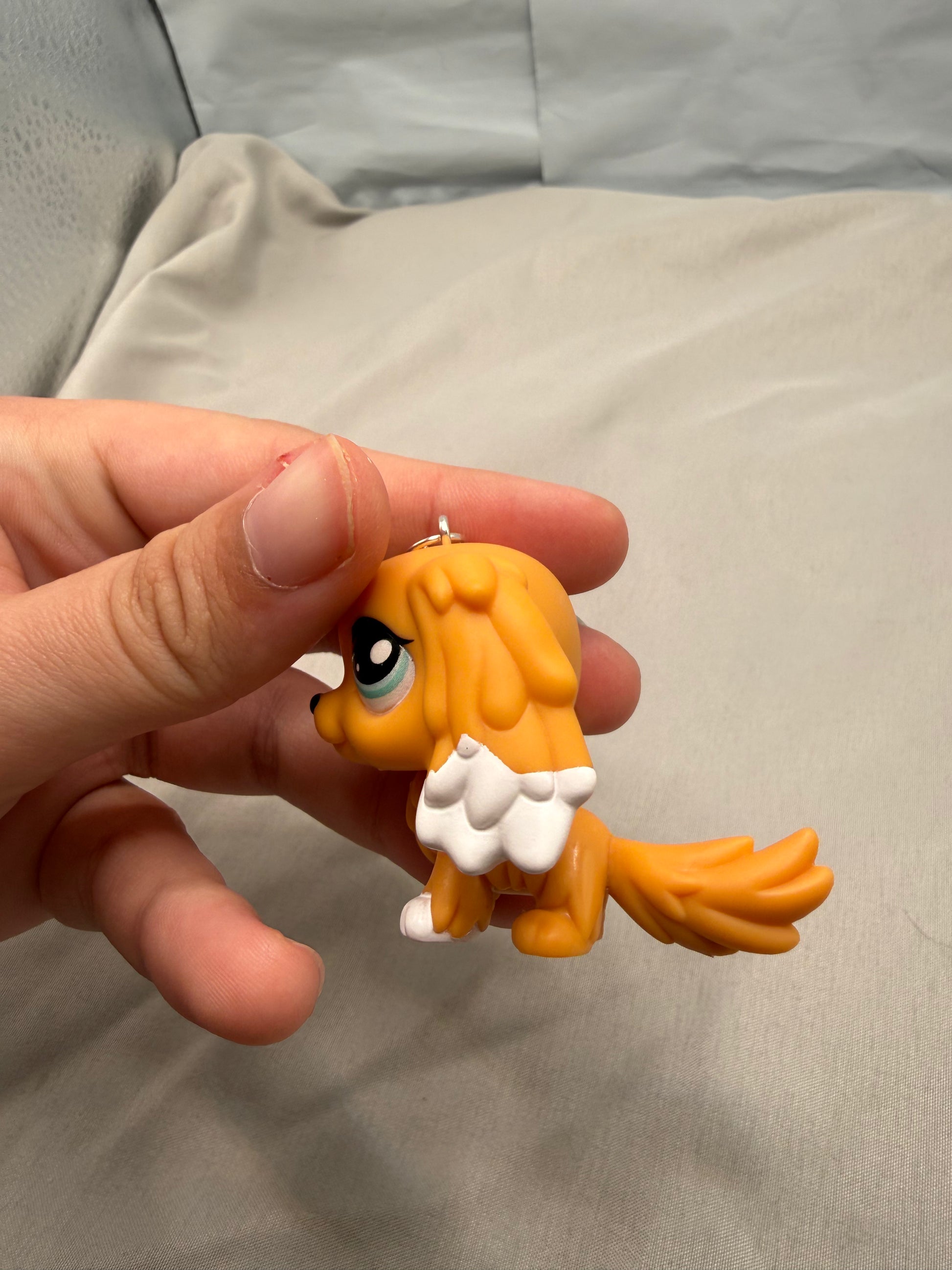 Small orange figurine held in a hand against a neutral background