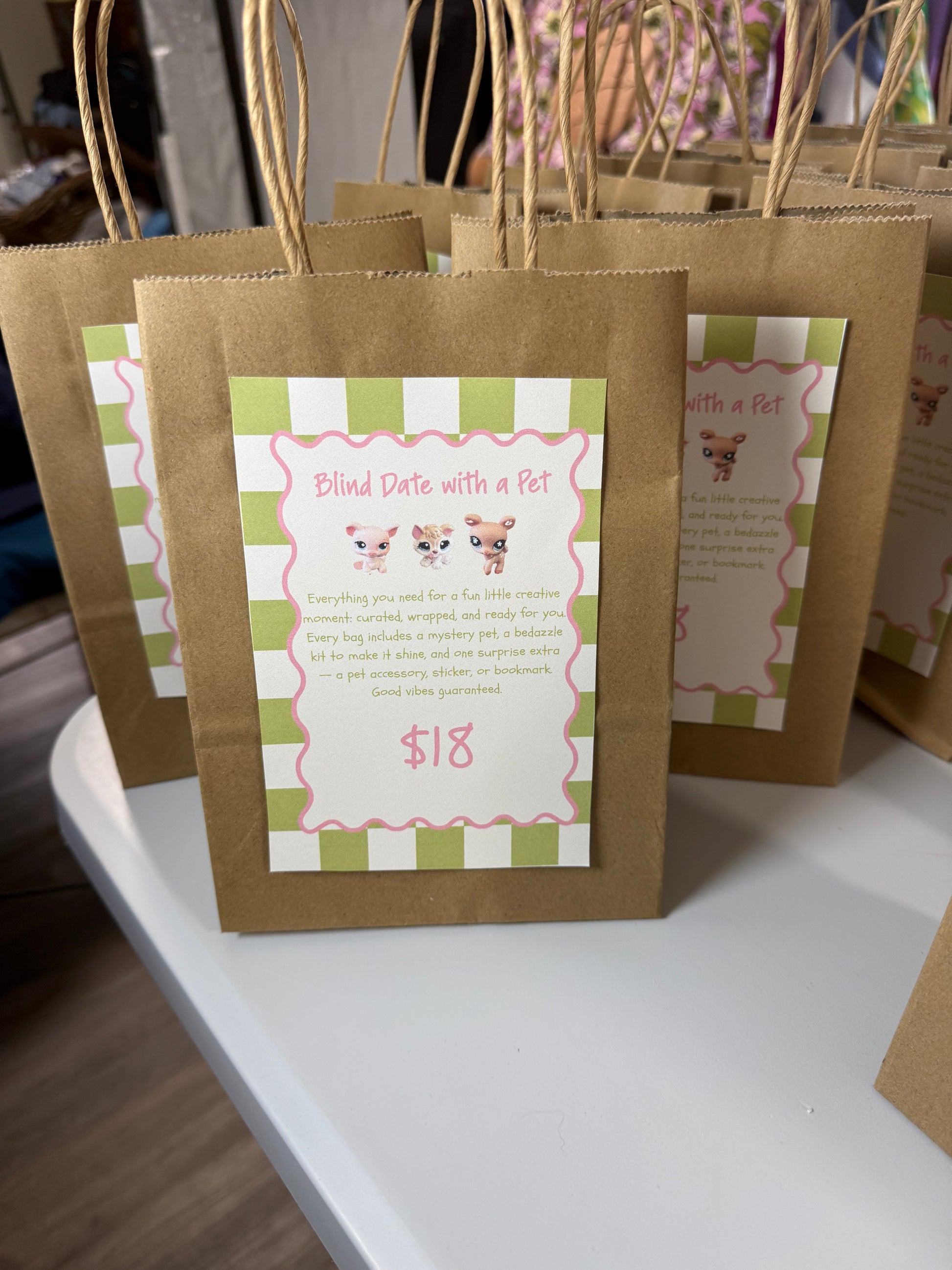 Brown kraft paper gift bags with twisted paper handles, each printed with a green-and-white striped label that reads 'Blind Date with a Pet' and shows a $18 price.