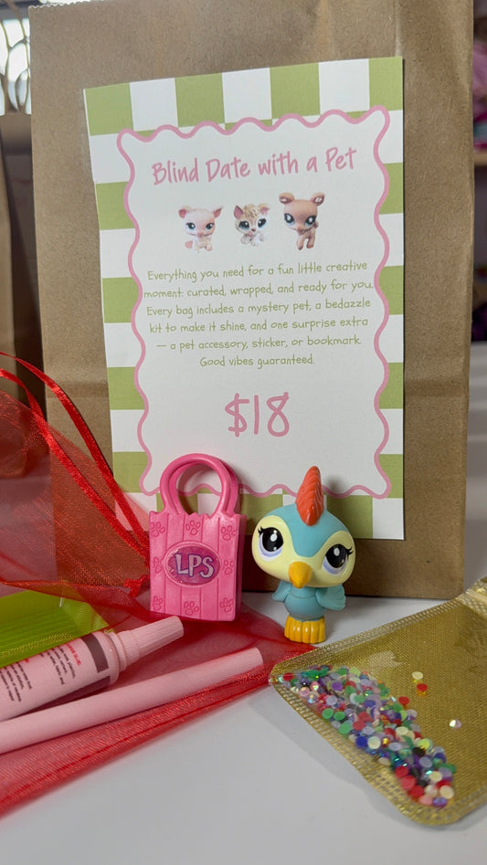 A 'Blind Date with a Pet' mystery pet kit displayed on a white surface in front of a brown kraft paper bag. The kit includes a pink lock-shaped pouch with 'LPS' on it, a small blue and yellow toy bird, a pink tube, a green and pink item, and a clear bag filled with colorful beads.