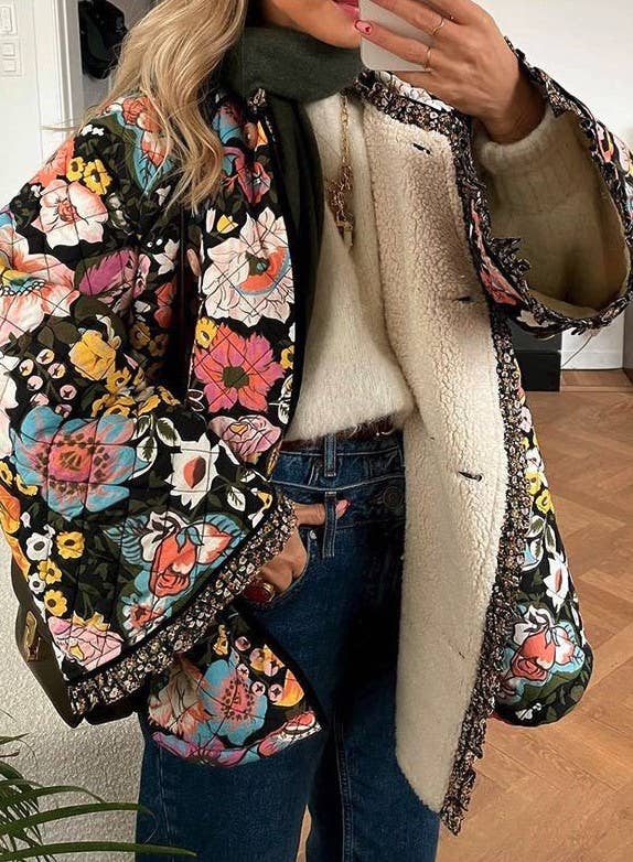 Person wearing a floral-patterned jacket with a white fleece lining, taking a mirror selfie.