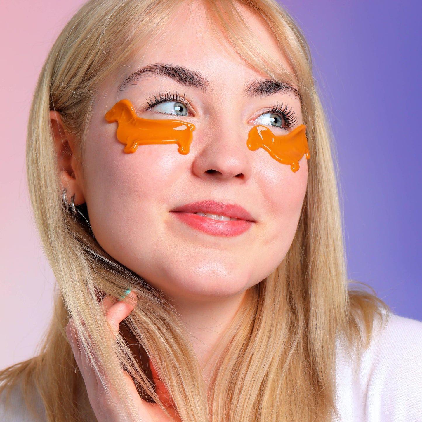 Woman wearing brown dachshund-shaped eye masks on a two-tone pink and purple background