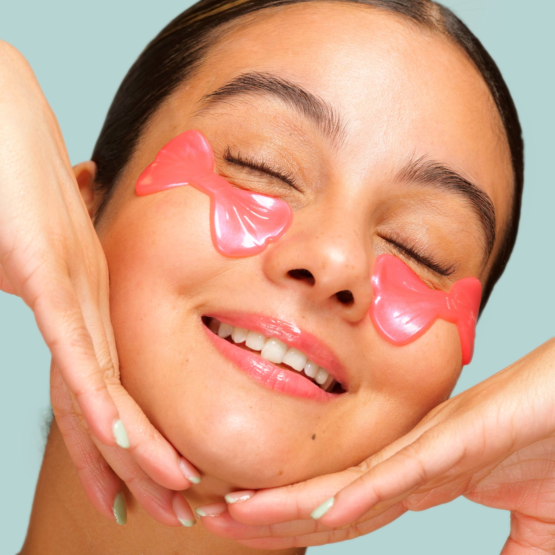 Woman with pink eye masks on her face against a light blue background