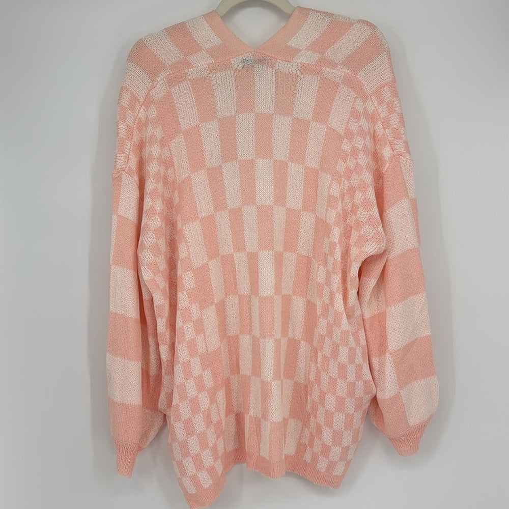 Pink checkered sweater on a hanger against a white background