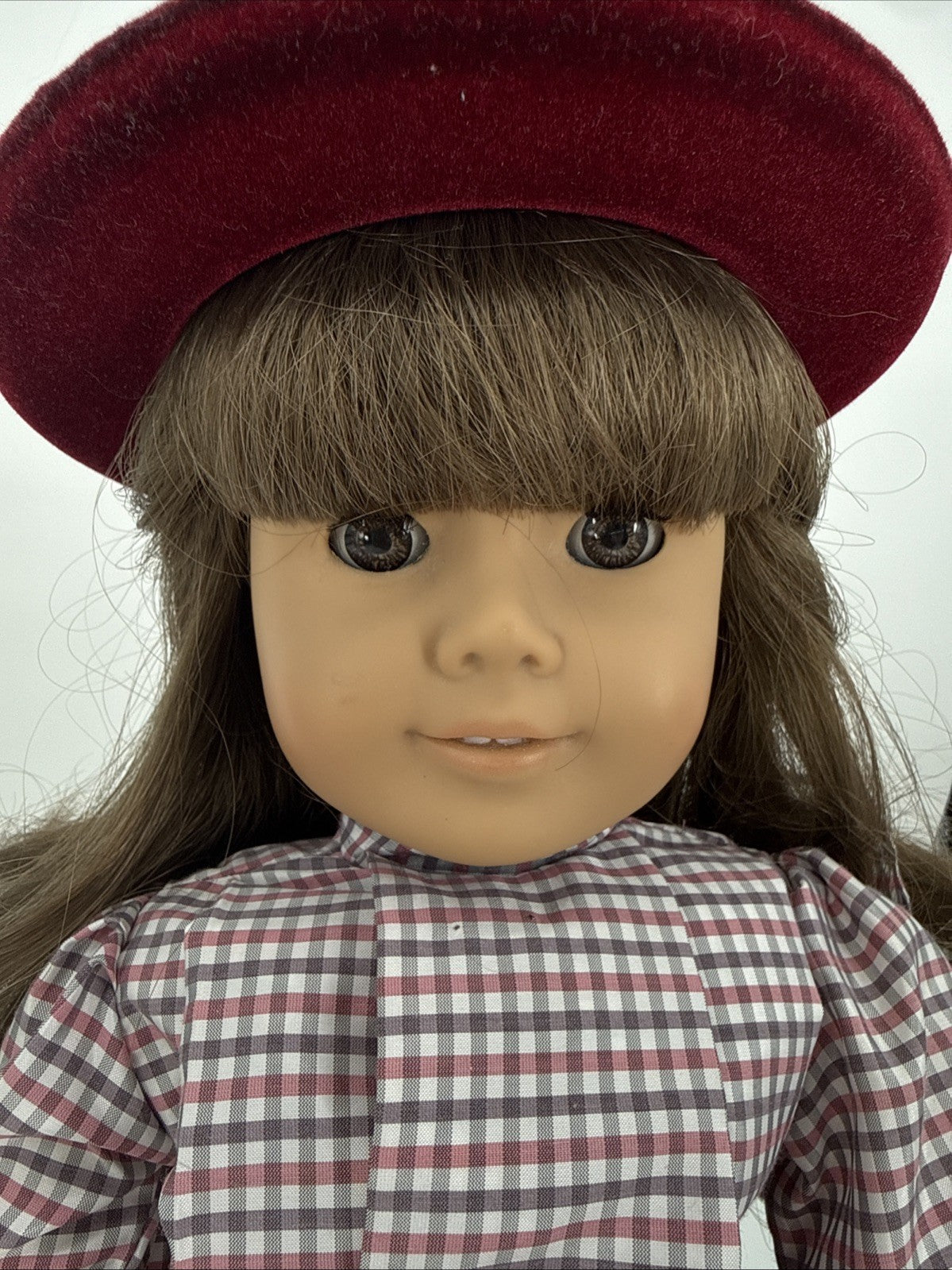 Doll with a red beret and checkered shirt on a white background