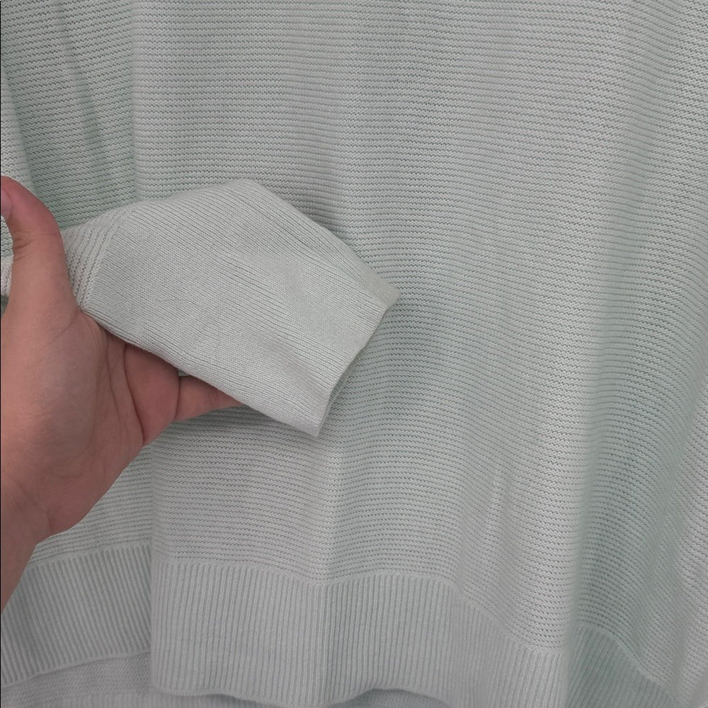 Light gray sweater with a hand holding a sleeve