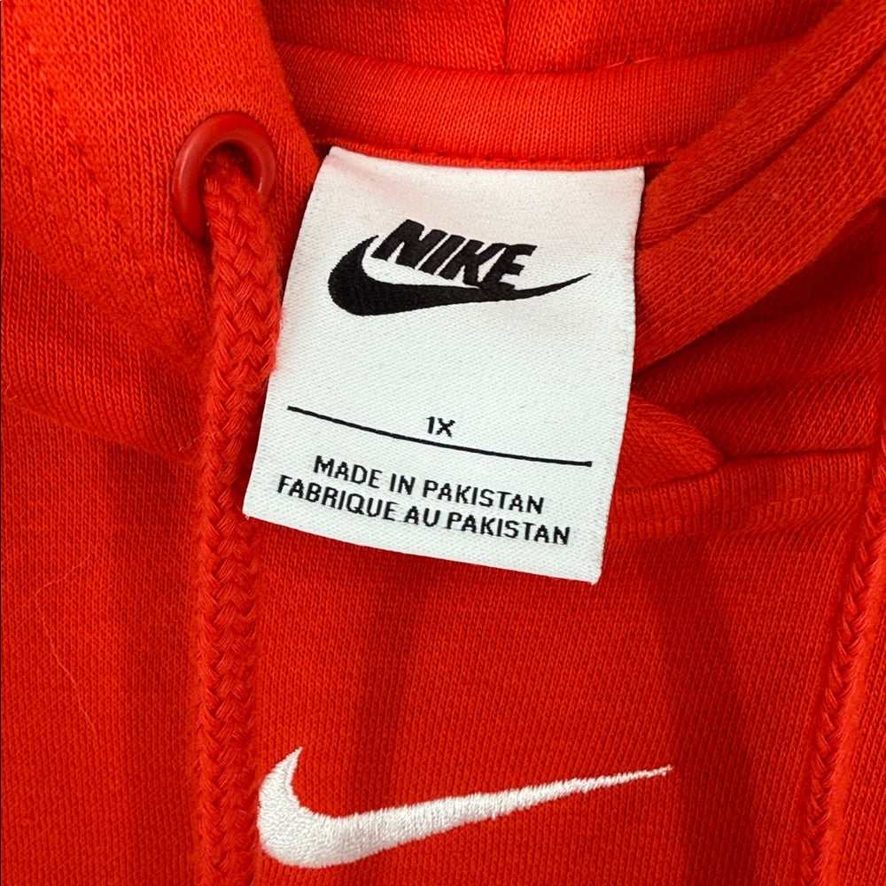 Close-up of a Nike label on a red garment with 'Made in Pakistan' text.