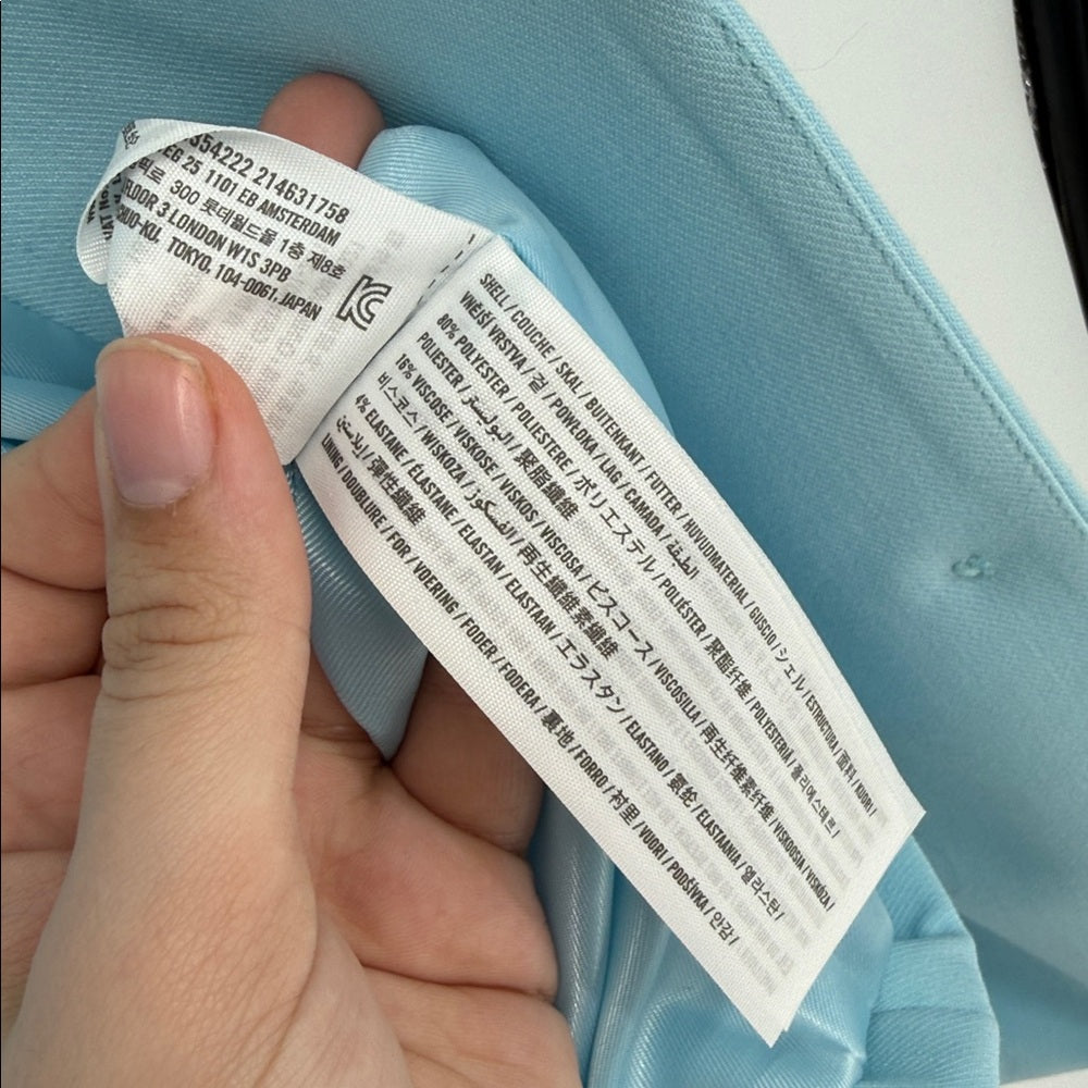 Hand holding a label with text on a light blue fabric background