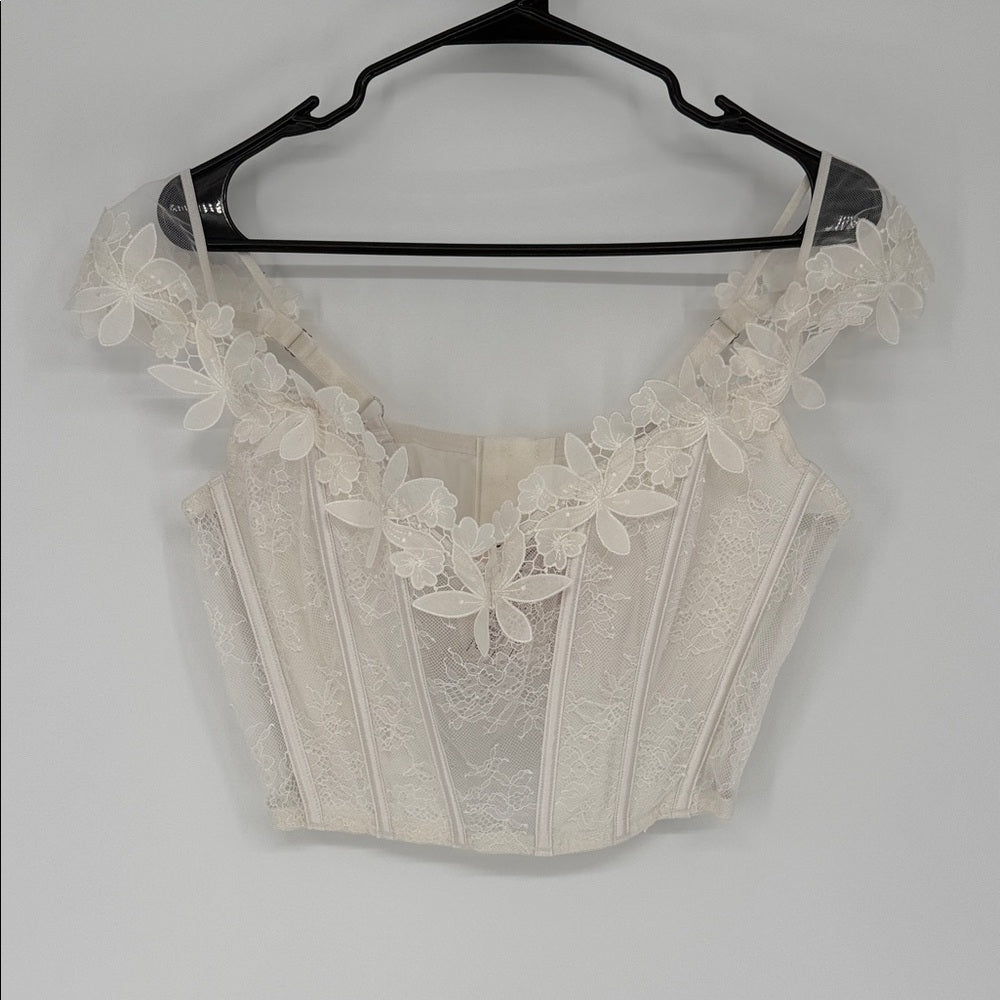 Beige lace crop top on a hanger against a white background