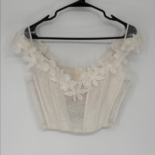 Beige lace crop top on a hanger against a white background