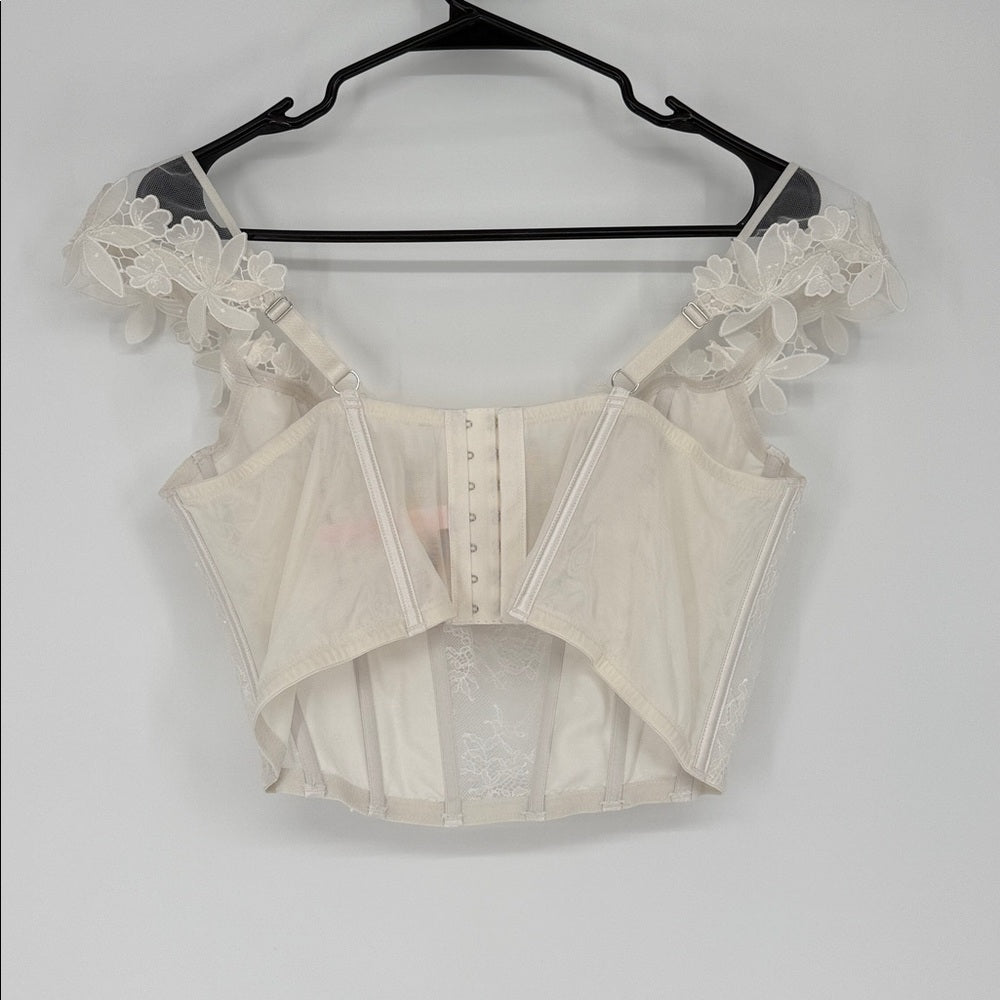 Beige lace top on a hanger against a white background