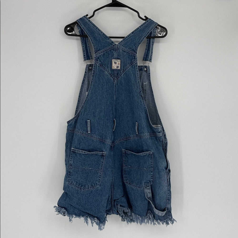 Blue denim overalls on a hanger against a white background