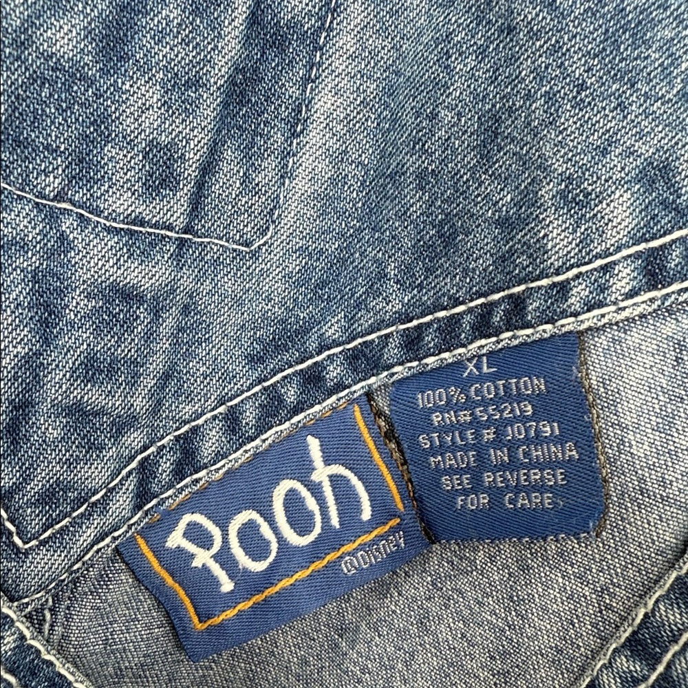 Close-up of a denim jacket label with 'Pooh' branding and text.