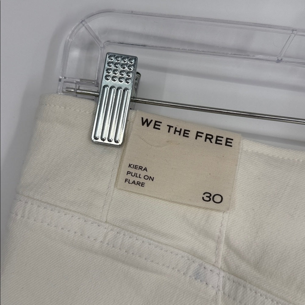 Beige pants with a 'WE THE FREE' label on a clear hanger against a white background