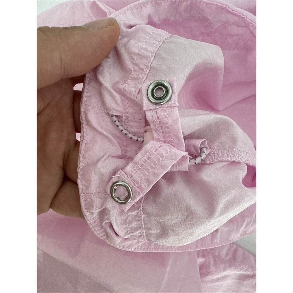 Close-up of pink fabric with grommets held by a hand on a white background