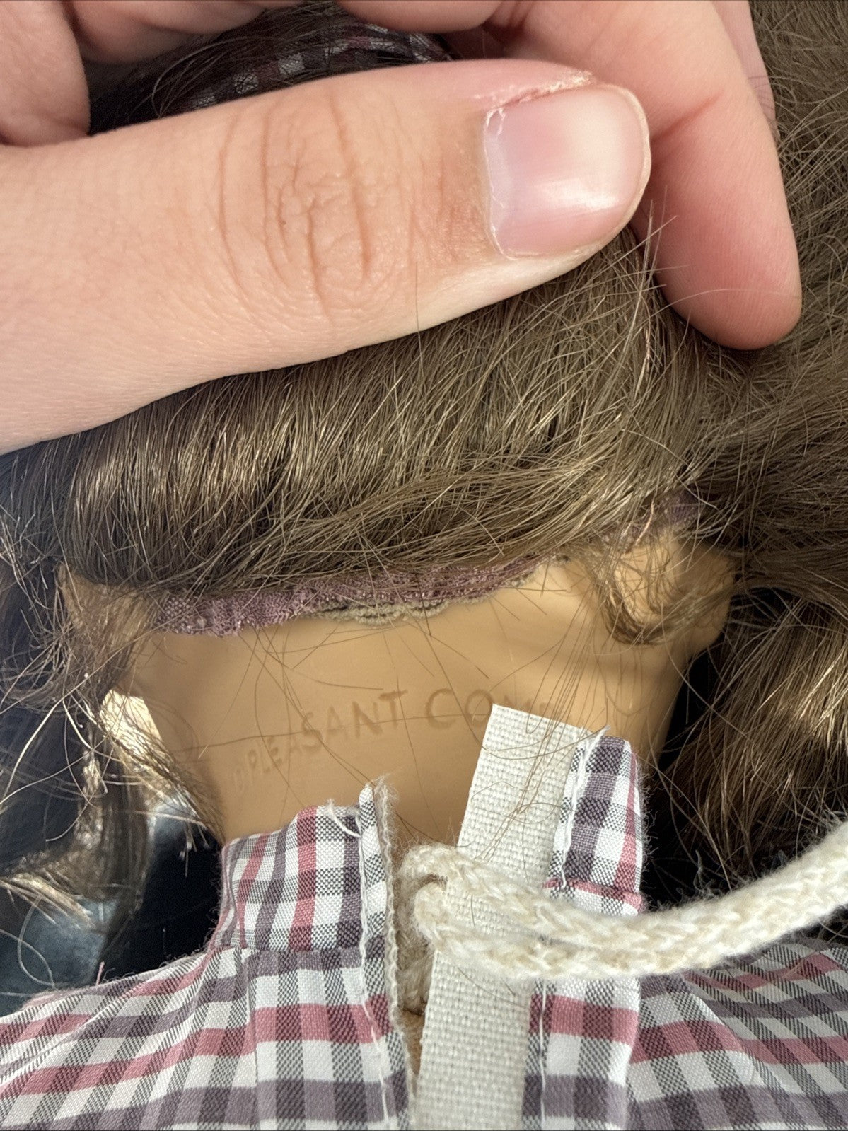 Close-up of a doll with a visible brand label, held by a person's hand.