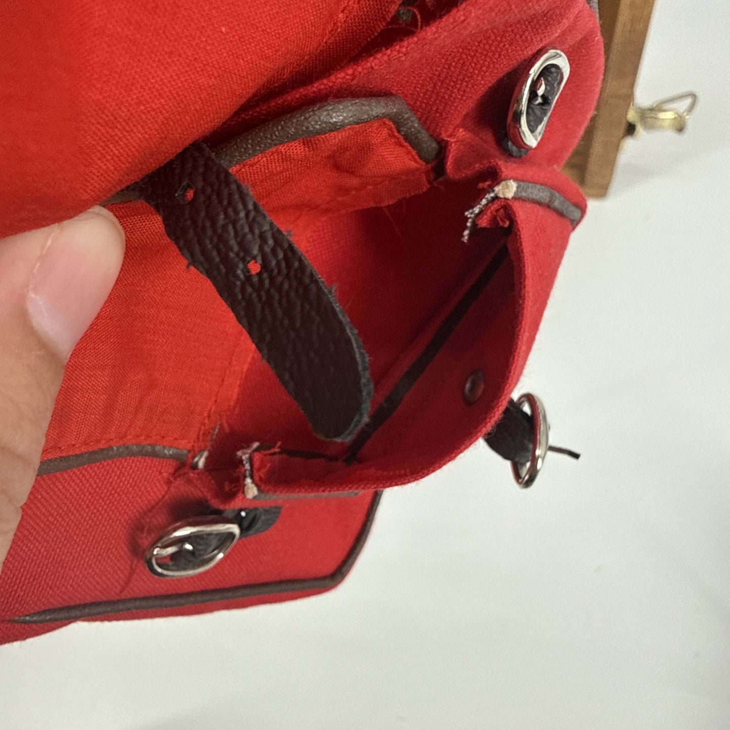 Close-up of a red bag with black accents held by a hand on a white background