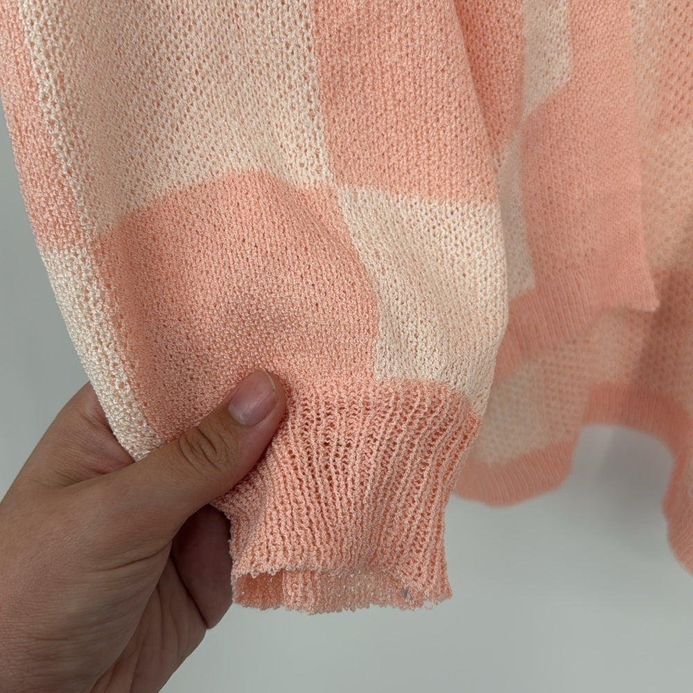 Hand holding a pink and beige checkered fabric against a neutral background