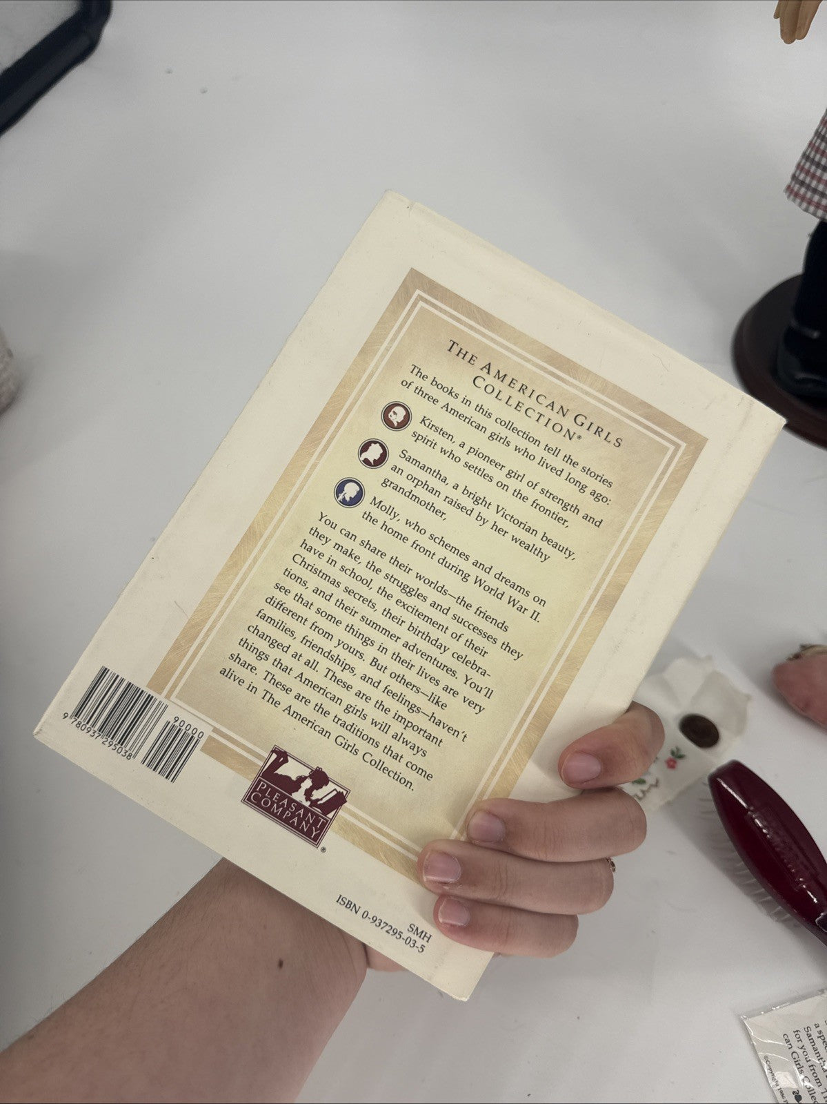 Back cover of a book held by a hand on a white surface