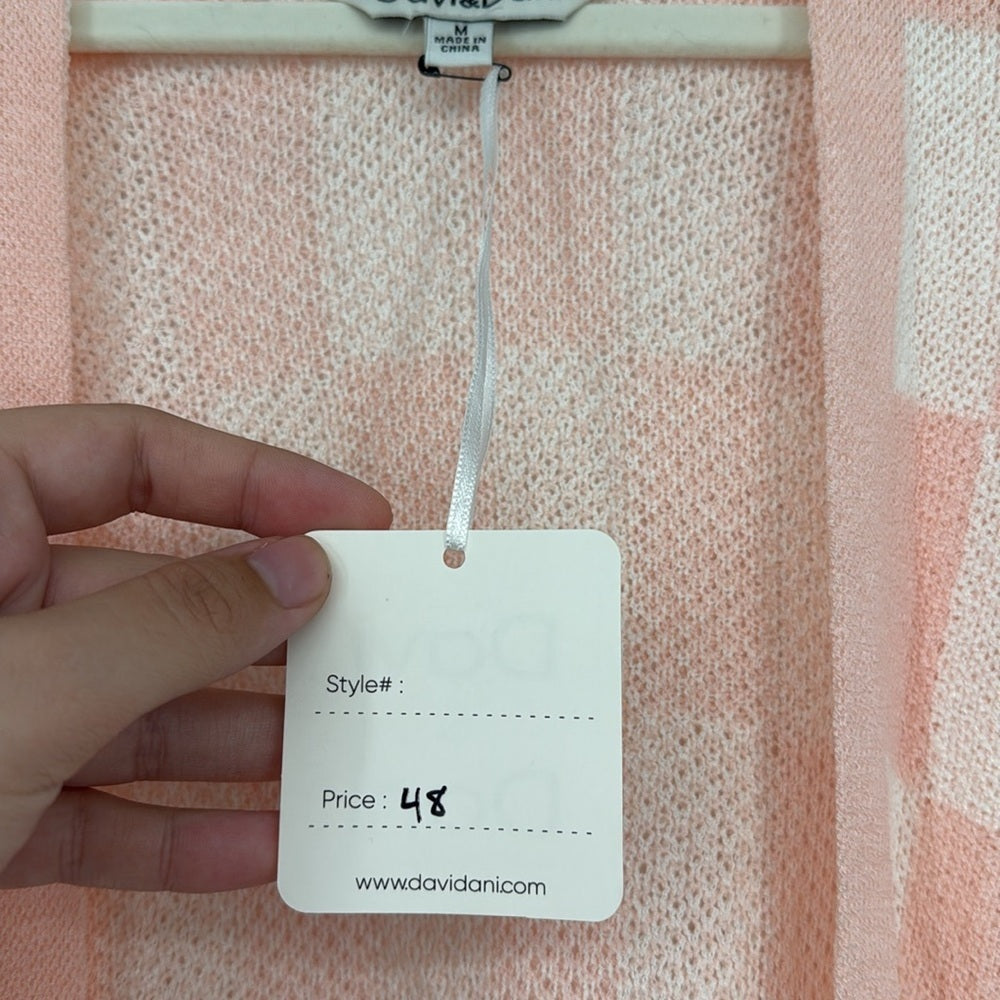 Hand holding a price tag against a pink textured fabric background