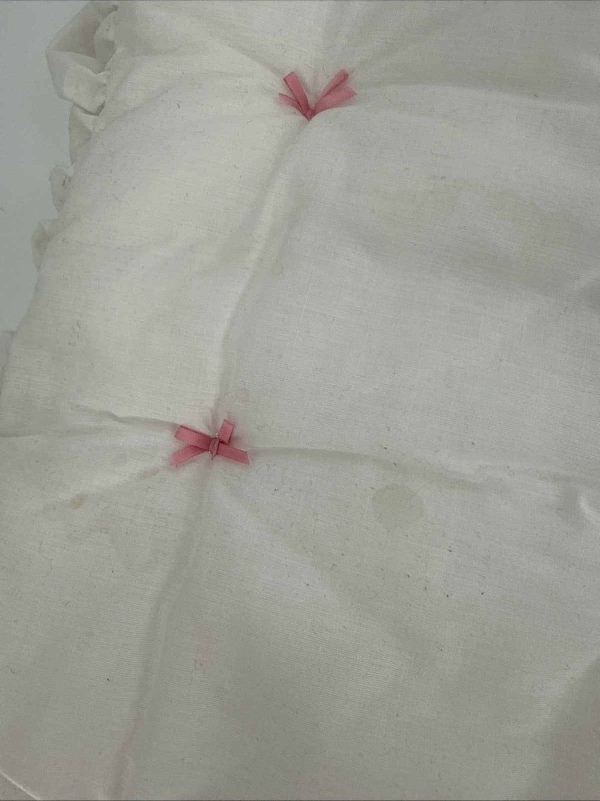 White fabric with pink decorative bows on a white background shows stain