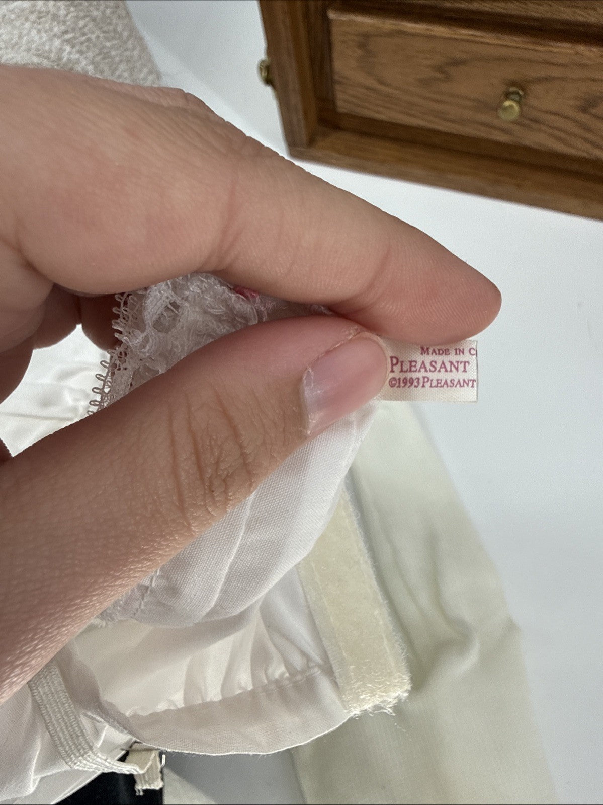 Close-up of a hand holding fabric with a Pleasant tag in the background