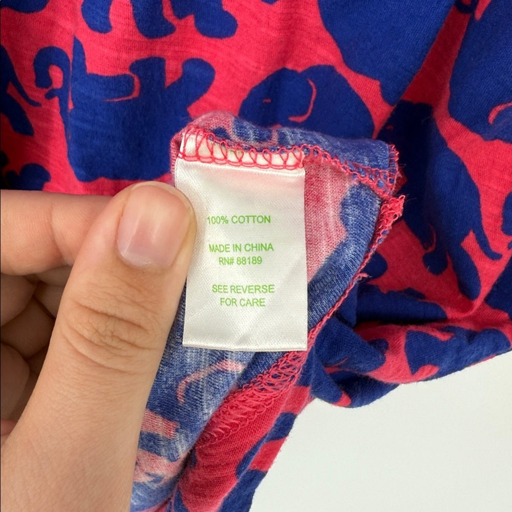 Hand holding a fabric tag with text on a red and blue patterned background