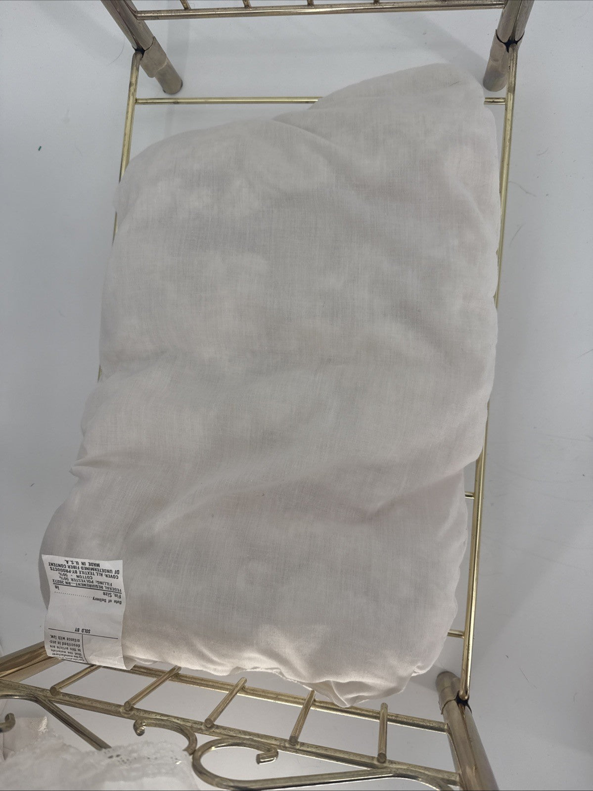 White pillow on a gold metal stand against a white background