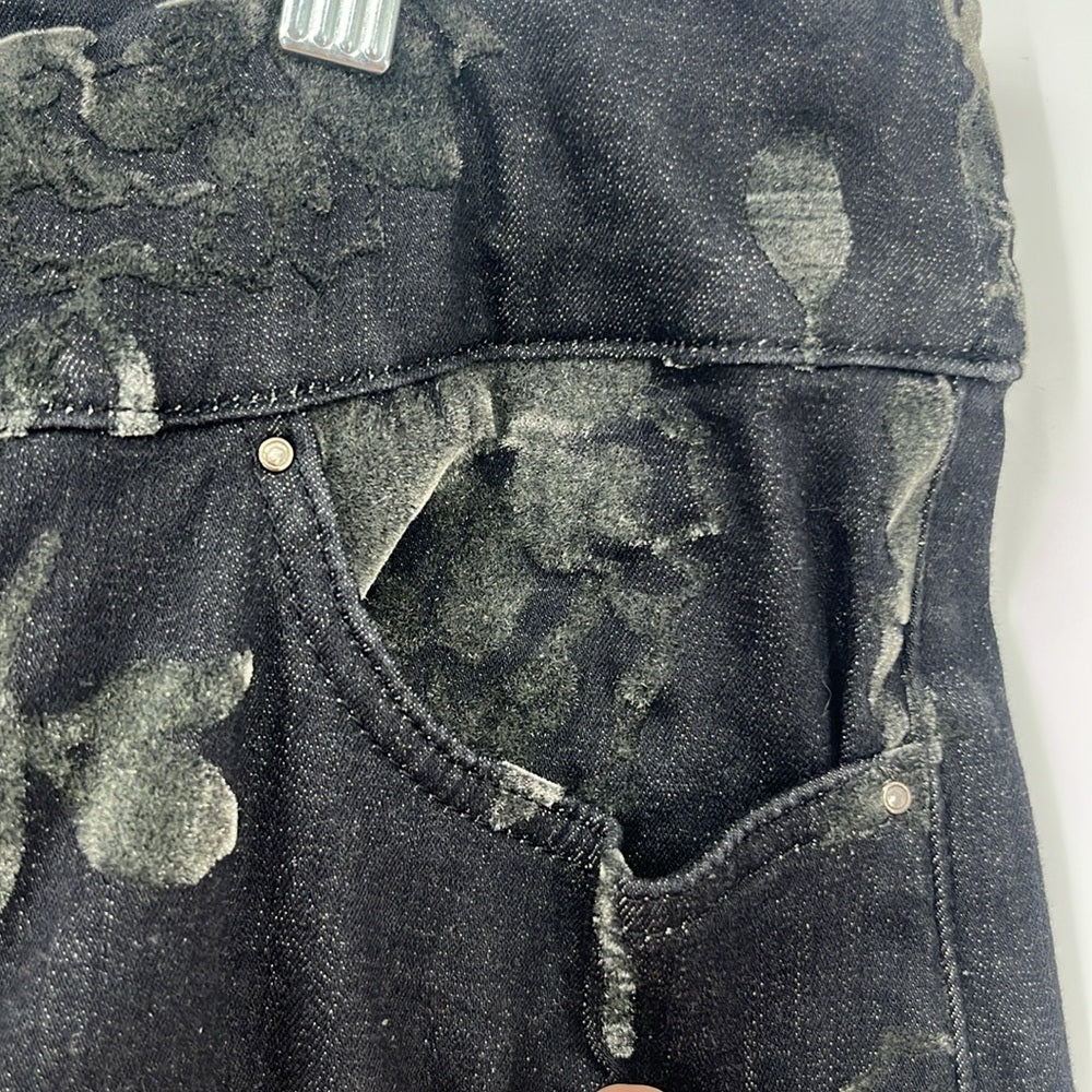 Close-up of a denim jacket with worn and patched design on a white background