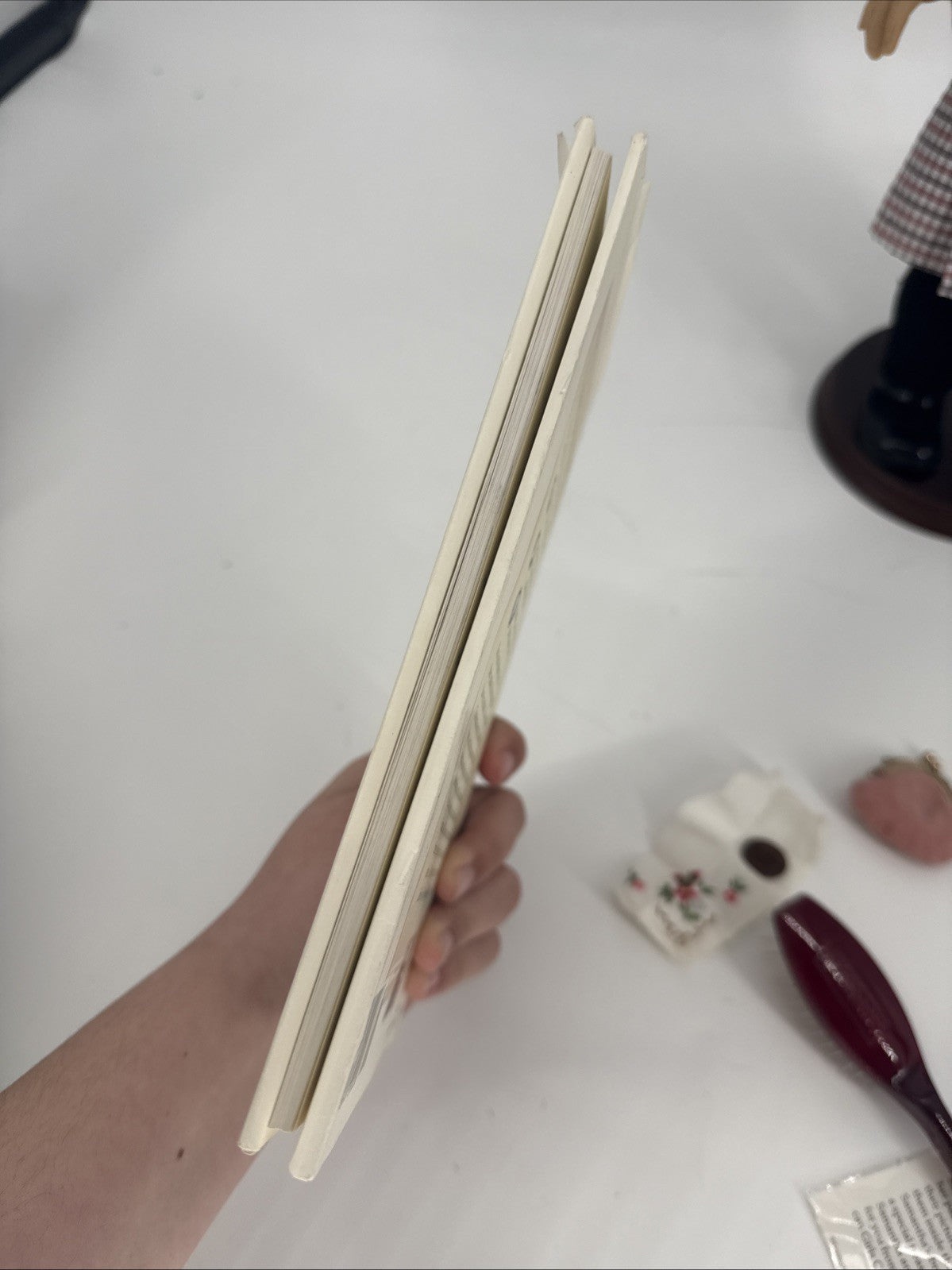 Hand holding a stack of wooden chopsticks on a white surface with blurred background