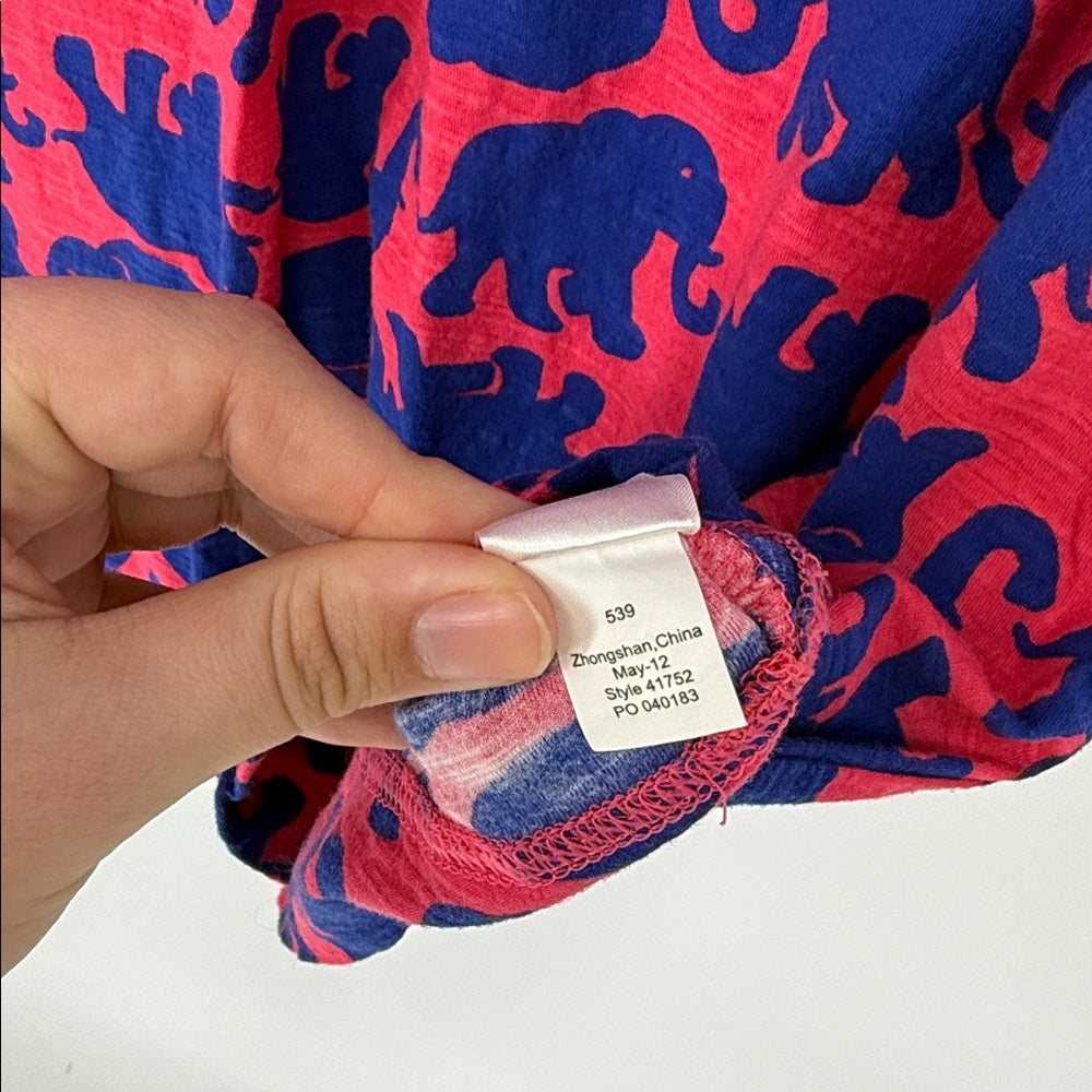 Close-up of a fabric with blue elephant pattern on red background, showing a label.